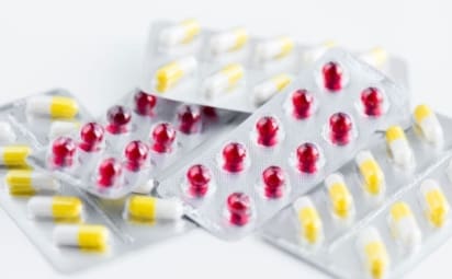 Red and yellow pills in foil packaging.