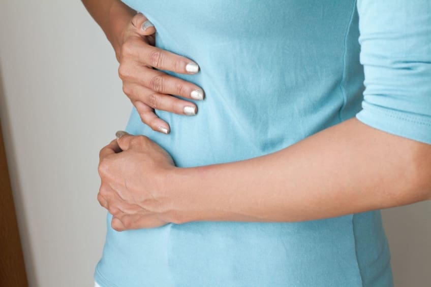 Woman with gallstones holds her stomach in pain