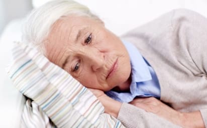 Elderly, depressed woman lying on pillow.