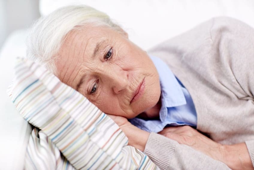 Elderly, depressed woman lying on pillow.
