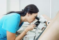 female gynecologist performing a colposcopy exam on a patient in hospital using a colposcope