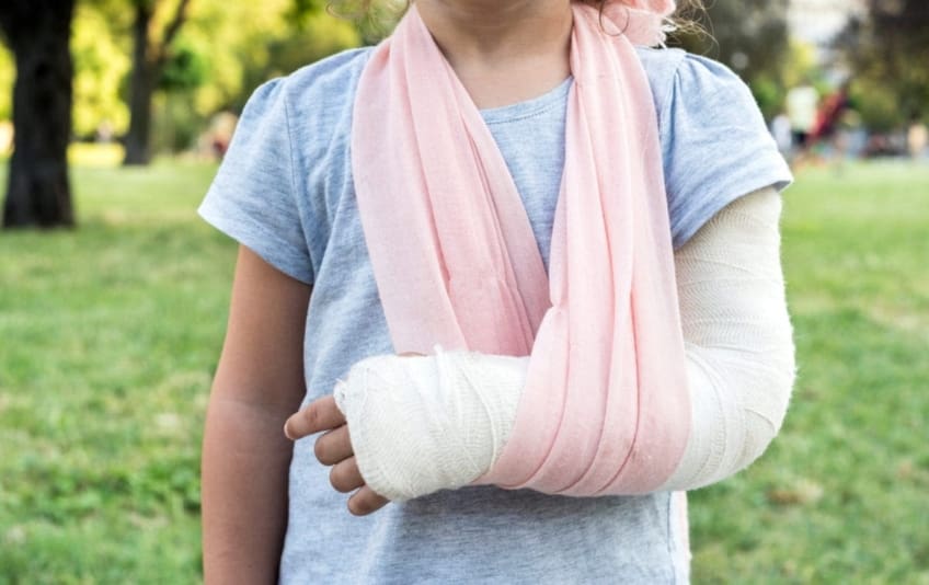 Child with broken arm and cast in sling