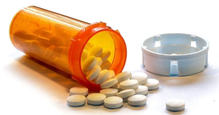 A prescription bottle containing nonsteroidal anti-inflammatory medicine spills out onto a table.
