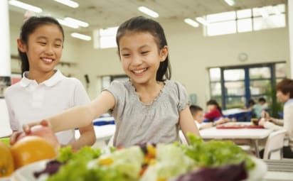 Students reaching for healthy food in school cafeteria