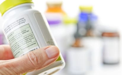 Hand holding medicine bottle to read label