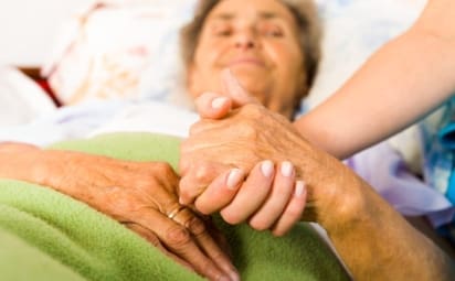 A woman suffering from dementia holds hands with a loved one