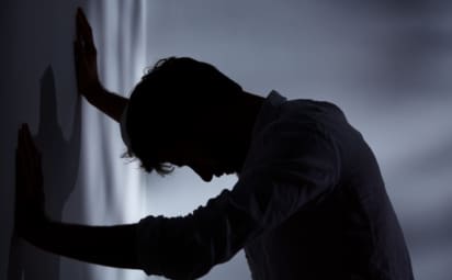 A man standing in the dark with his hands against the wall. If you are depressed or contemplating suicide, there is help. Suicidal thoughts often are caused by a treatable health problem.