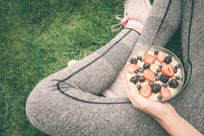 Athlete sitting and holding a bowl of oatmeal and berries in lap