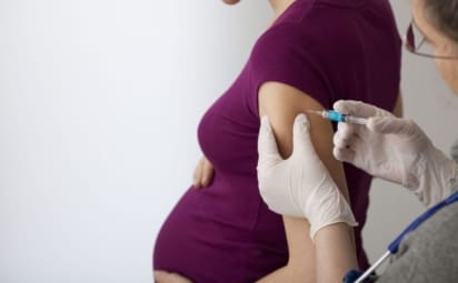 A pregnant woman gets a flu shot in the arm.