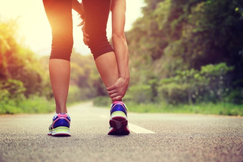 Woman in exercise clothing and holding her ankle