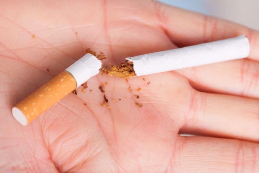 . Closeup of the broken cigarette on female hand.