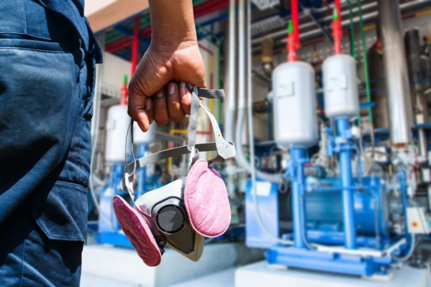 Man in an industrial factory, holding a respirator to prevent occupational respiratory disease