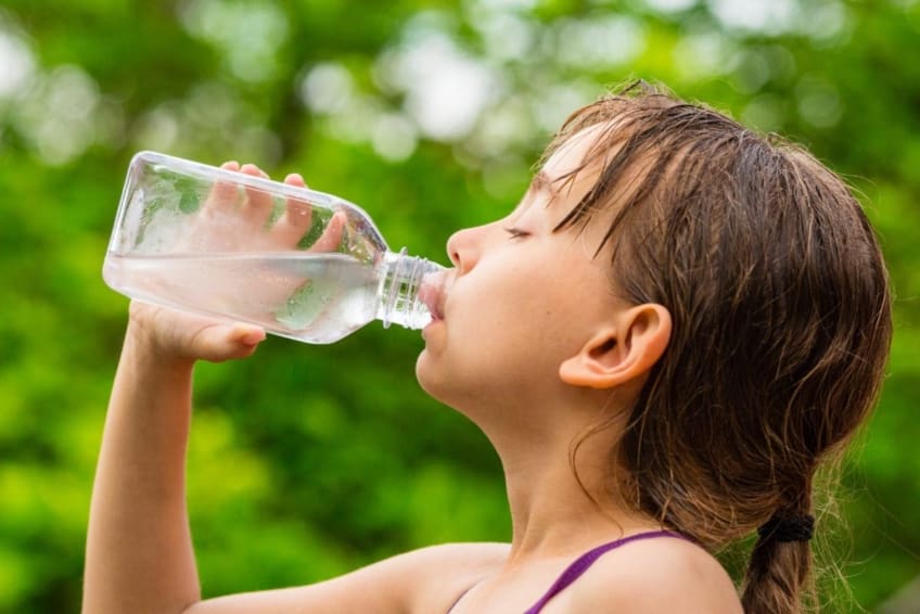 sweaty girl drinking water from a bottle outside
