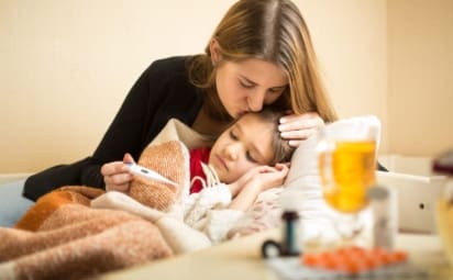 A young caring mother kisses her sick daughter's head. Cold and flu season often begins in October as the weather outside starts to turn cold. It can last until May. Each year, it’s important to prepare and protect your family from these illnesses.