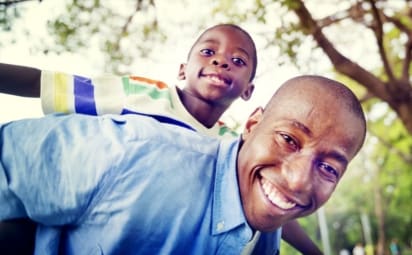 smiling father gives son a piggy-back ride outside
