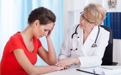 Doctor holds the hand of a depressed female patient.