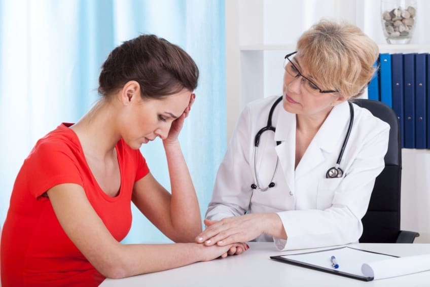 Doctor holds the hand of a depressed female patient.