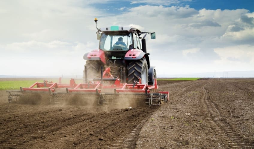 A red tractor plowing a field