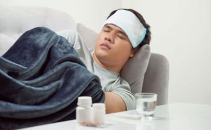 A sick man sleeps on the couch next to a table with medication and a glass of water. These days, when you’re feeling under the weather with a fever, body aches, and other symptoms, you may wonder whether you have season influenza (flu) or COVID-19. The two share many similarities, but there are a few differences.