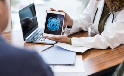 A doctor shows her patient a brain scan to explain a test result and diagnosis.